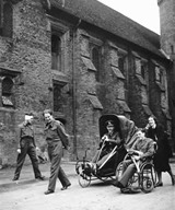 Outside the Old Palace at Hatfield House. "Handle-bar Hanks"  in 'pram' and Anne Cloudsley pushing the disabled chair.