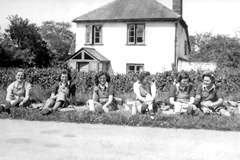 Lilian, Mary, Betty, Sadie, Bessie and Nora break for lunch on their way to another farm (1943/44).The photograph was taken by a convoy of American troops who drew up to a sudden halt on seeing the girls on the grass verge!
