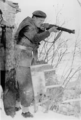Denis Forman aiming a rifle, with Italian Partisans c.1943