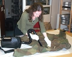Ruth Darling (MA Museum Studies student) uses a museum vacuum to clean a uniform. 