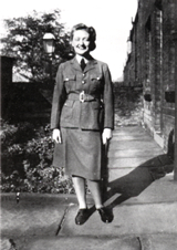 Joan Tiplady with crisply pressed creases in her skirt, changing it from
          a 'tube skirt' into a more fashionable 'cube skirt'.
